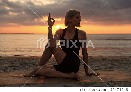 woman doing yoga lord of the fishes pose on beach 93471948