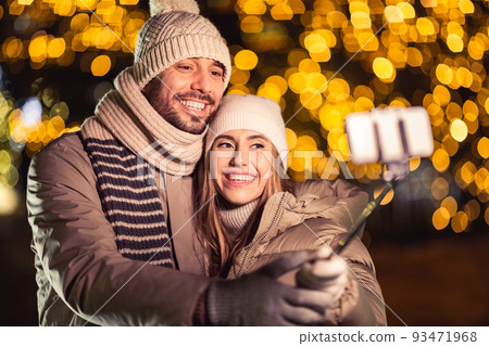 happy couple taking selfie over christmas lights 93471968