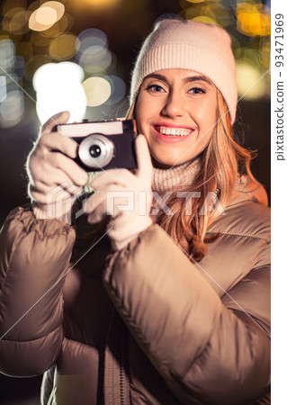 happy woman with camera over christmas lights 93471969
