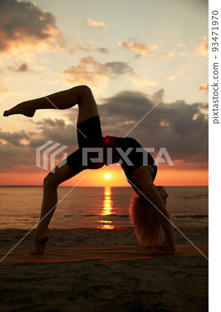 woman doing yoga bridge pose on beach woman doing yoga bridge pose on beach 93471970