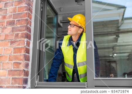 male builder in helmet looking out window male builder in helmet looking out window 93471974