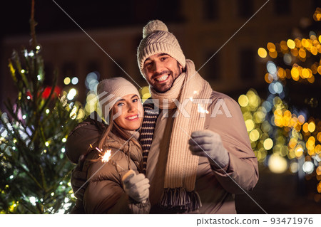 happy couple with sparklers over christmas lights happy couple with sparklers over christmas lights 93471976