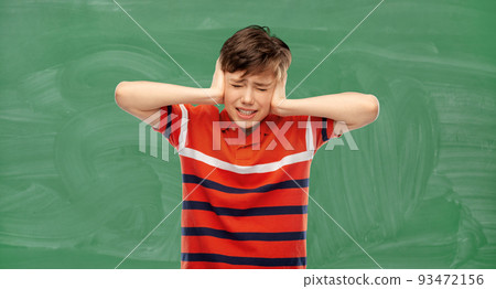stressed student boy closing ears over chalkboard 93472156