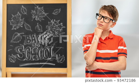 thinking student boy in eyeglasses over chalkboard 93472186