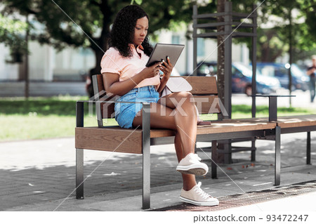 african american woman with tablet pc in city 93472247