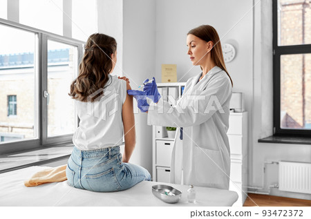 female doctor with syringe vaccinating patient 93472372