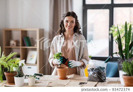 happy woman planting pot flowers at home happy woman planting pot flowers at home 93472374