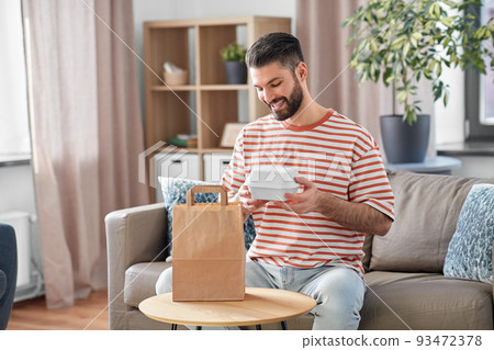 smiling man unpacking takeaway food at home smiling man unpacking takeaway food at home 93472378