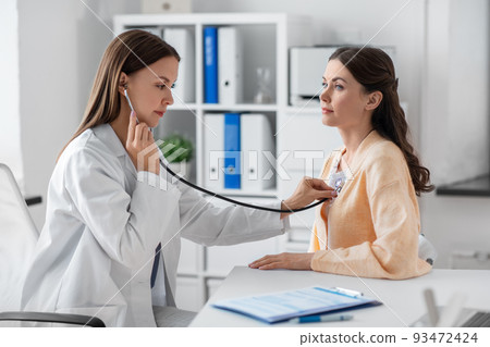 doctor with stethoscope and woman at hospital 93472424