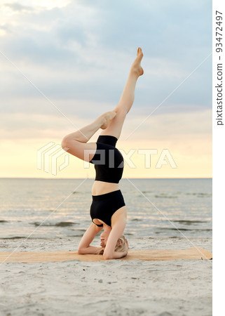 woman doing yoga headstand on beach woman doing yoga headstand on beach 93472497