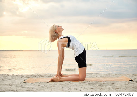 woman doing yoga camel pose on beach woman doing yoga camel pose on beach 93472498