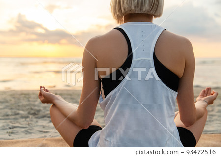 woman meditating in lotus pose on beach 93472516