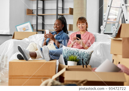 women with smartphones moving into new home women with smartphones moving into new home 93472722