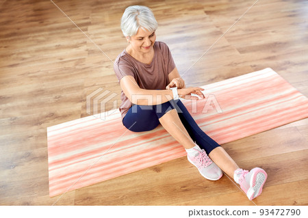 smiling senior woman with fitness tracker at home 93472790