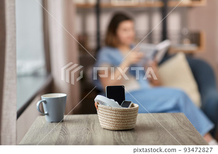 gadgets in basket on table and woman reading book gadgets in basket on table and woman reading book 93472827
