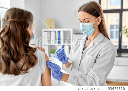 female doctor with syringe vaccinating patient 93472830