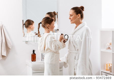 mother and daughter applying make up in bathroom mother and daughter applying make up in bathroom 93472869
