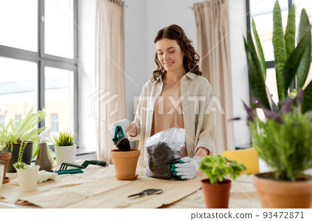 happy woman planting pot flowers at home 93472871