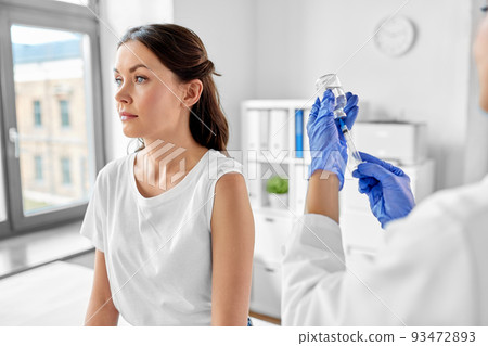 female doctor with syringe vaccinating patient 93472893