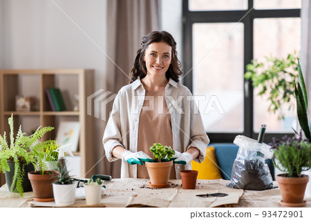 happy woman planting pot flowers at home happy woman planting pot flowers at home 93472901