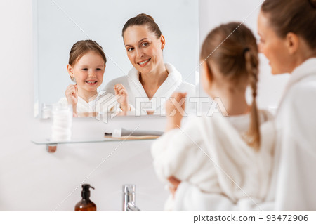 mother and daughter with floss cleaning teeth mother and daughter with floss cleaning teeth 93472906