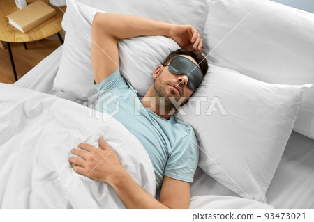 man in eye mask sleeping in bed at home 93473021