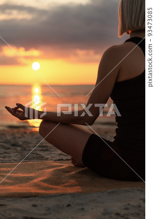 woman meditating in lotus pose on beach woman meditating in lotus pose on beach 93473085