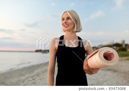 happy woman with yoga mat on beach 93473086