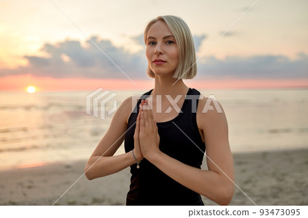 woman meditating on beach over sunset 93473095