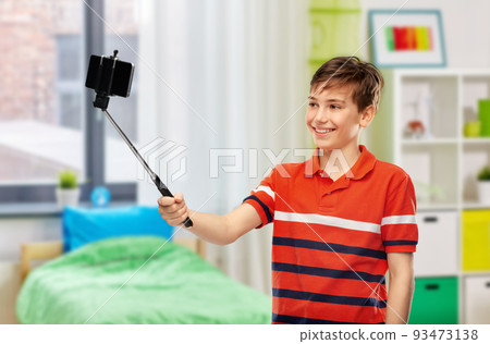 happy boy taking selfie with smartphone at home 93473138
