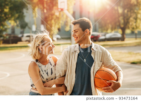 happy couple with ball on basketball playground 93473164
