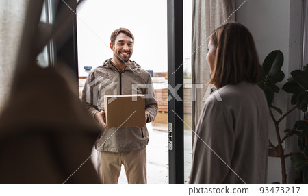 delivery man with parcel box and customer at home 93473217