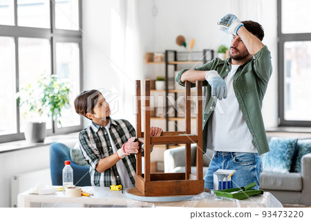 tired father and son sanding old table with sponge 93473220