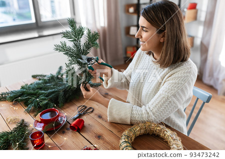 happy woman making fir christmas wreath at home happy woman making fir christmas wreath at home 93473242