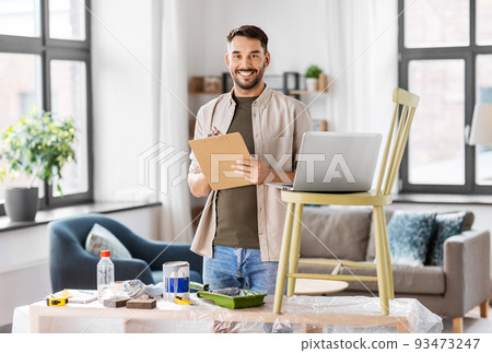 man with clipboard and laptop renovating old chair man with clipboard and laptop renovating old chair 93473247