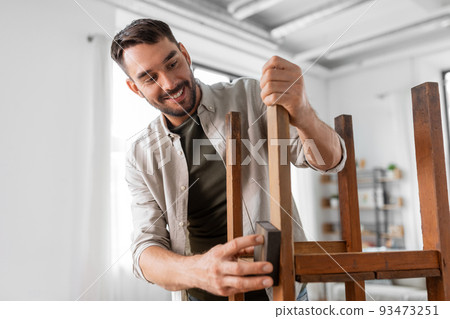 man sanding old round wooden table with sponge man sanding old round wooden table with sponge 93473251