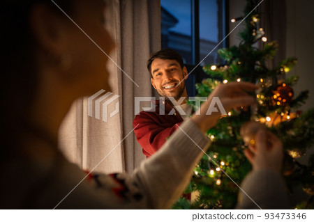 happy couple decorating christmas tree at home happy couple decorating christmas tree at home 93473346