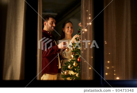 happy couple decorating christmas tree at home happy couple decorating christmas tree at home 93473348