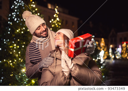happy couple with gift over christmas lights 93473349