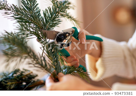 happy woman making fir christmas wreath at home 93473381