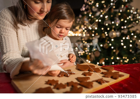 mother and daughter decorating gingerbread at home 93473385