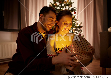 happy couple opening christmas gift at home happy couple opening christmas gift at home 93473387
