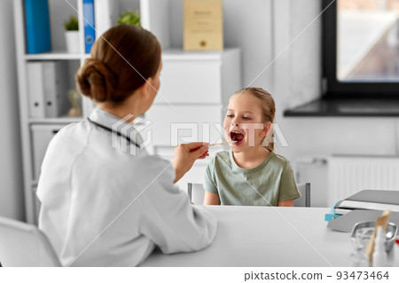 doctor checking girl patient's throat at clinic 93473464