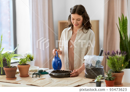 happy woman planting pot flowers at home happy woman planting pot flowers at home 93473623
