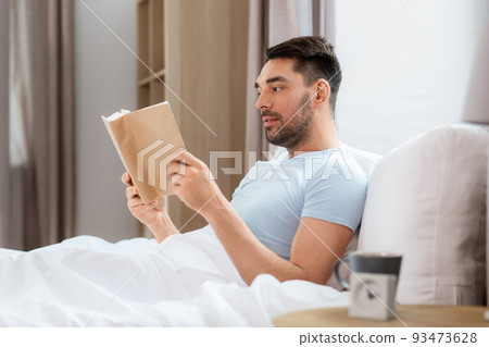 man reading book in bed at home man reading book in bed at home 93473628