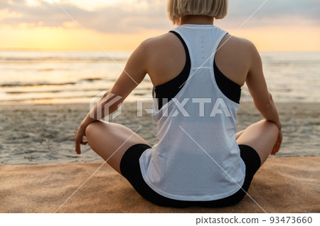 woman meditating in lotus pose on beach woman meditating in lotus pose on beach 93473660