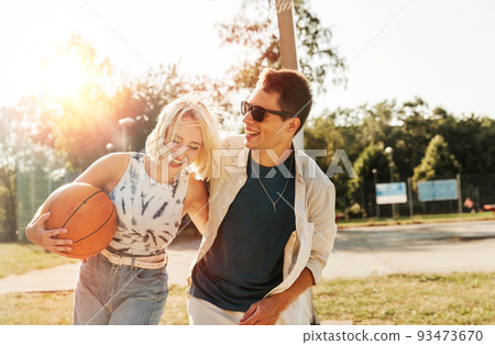 happy couple with ball on basketball playground 93473670