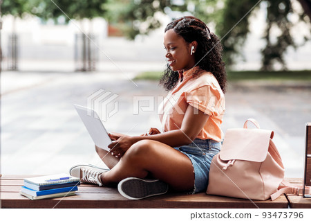 african student girl in earphones with laptop 93473796