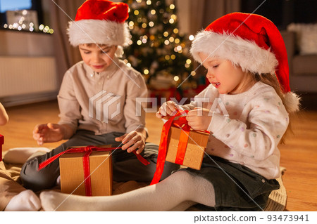 happy children opening christmas gifts at home 93473941