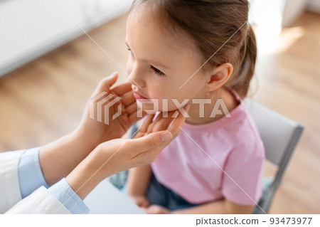 doctor checking girl patient's tonsils at clinic 93473977